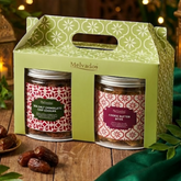 Two jars of Melvados cookie butter in a decorative green box with festive lights in the background.